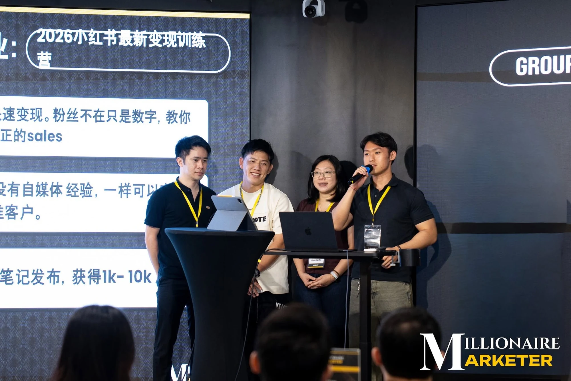 Travis at the right, holding a microphone at an event